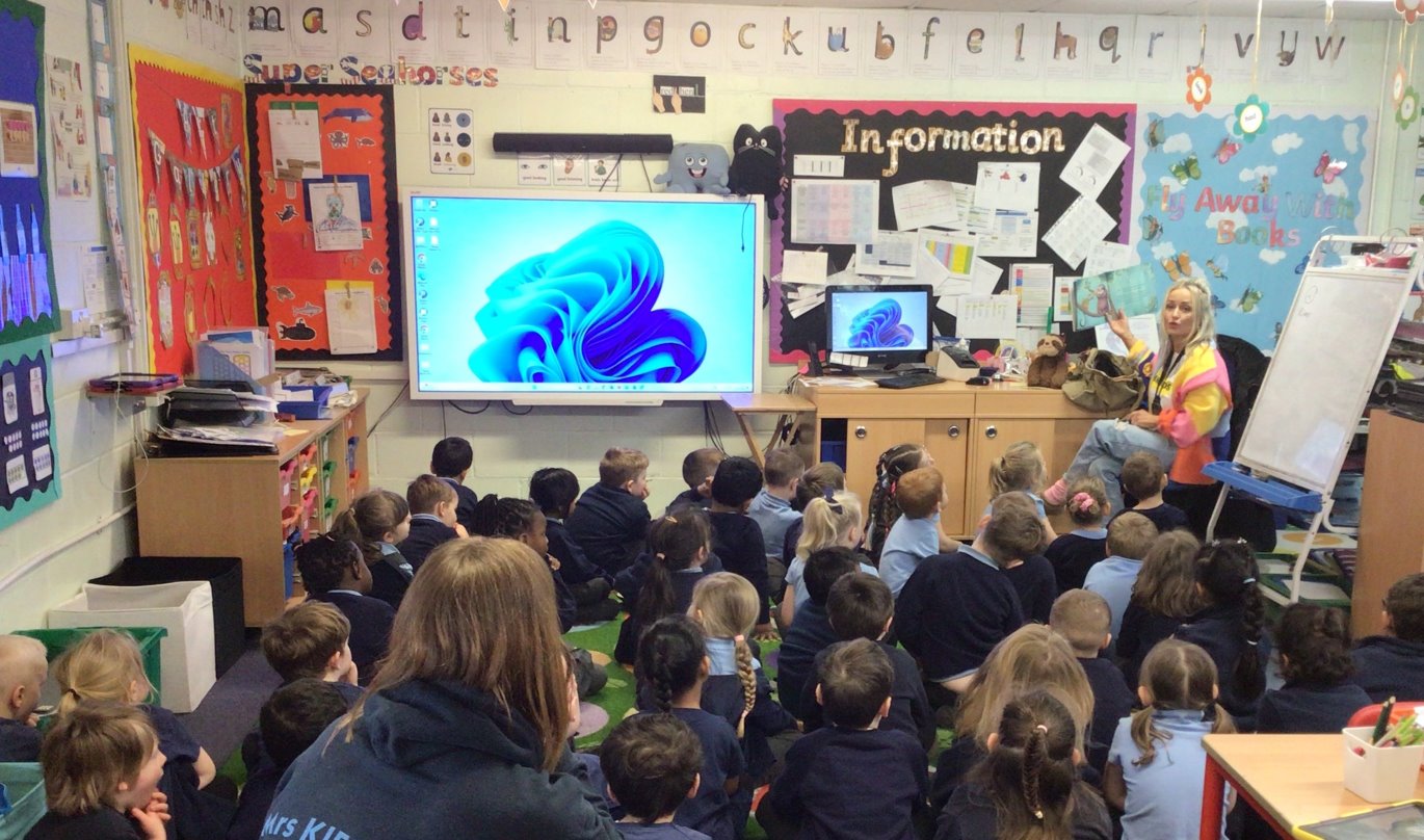 school-visits eliza allen sitting at the head of a class explaining her books to the pupils